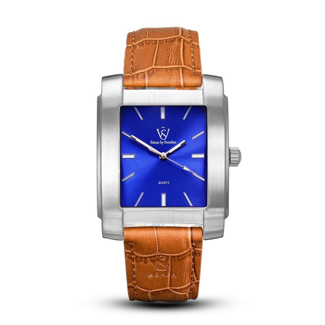 The Legacy Majorca, a square watch from Söner, features a stainless steel design with a blue dial and silver hour markers, elegantly displaying the logo. It comes with a brown leather strap accented by a sophisticated crocodile pattern.