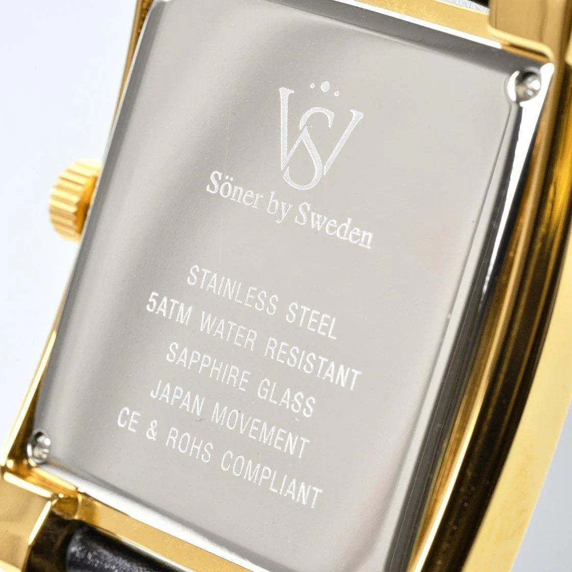 Close-up of the Momentum Astoria watch case back showing engraved details including stainless steel construction, 5 ATM water resistance, sapphire glass, Japanese movement, and compliance markings.