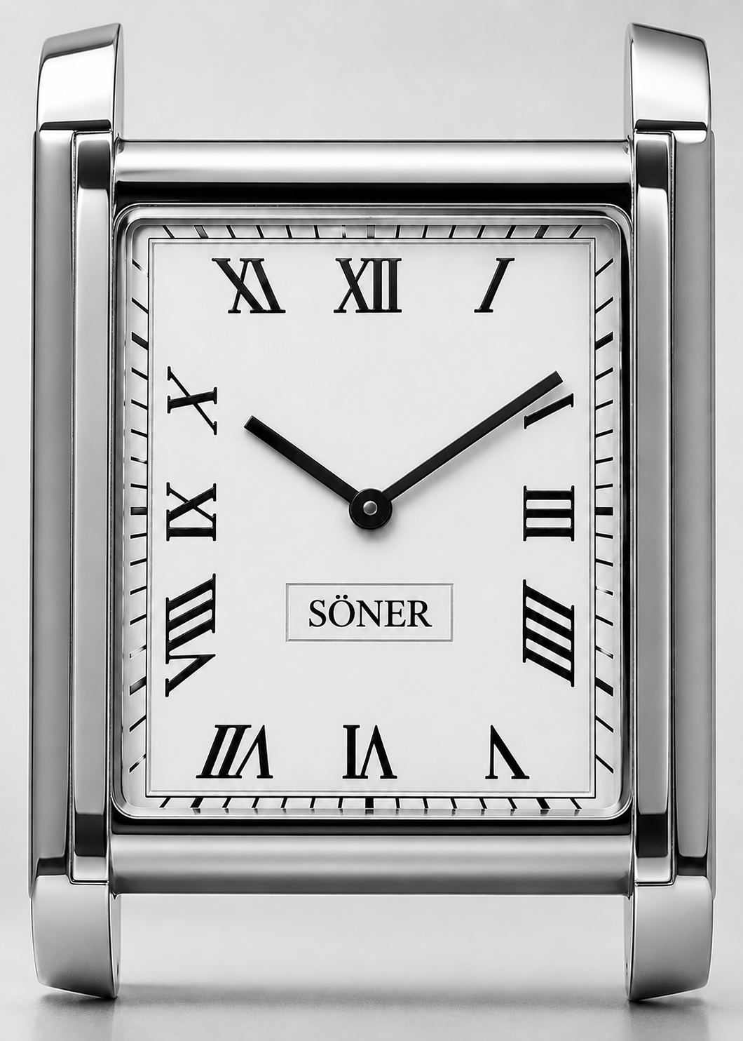 A silver desk clock with Roman numerals, black hands, and the word SÖNER at the center of the white face. The time shown is 10:10. Inspired by classic Art Deco watch design, the frame features a modern, polished metal style reminiscent of a Tank Watch.