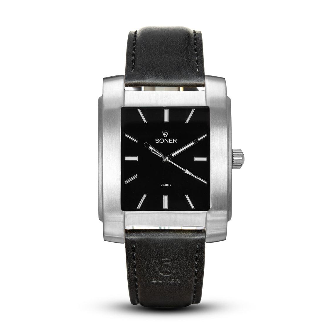 A square watch from Söner's Legacy Basilica collection, featuring a black dial with silver hour markers and a sleek silver case. It boasts a finely crafted black leather strap and prominently displays the Soner brand on the dial.