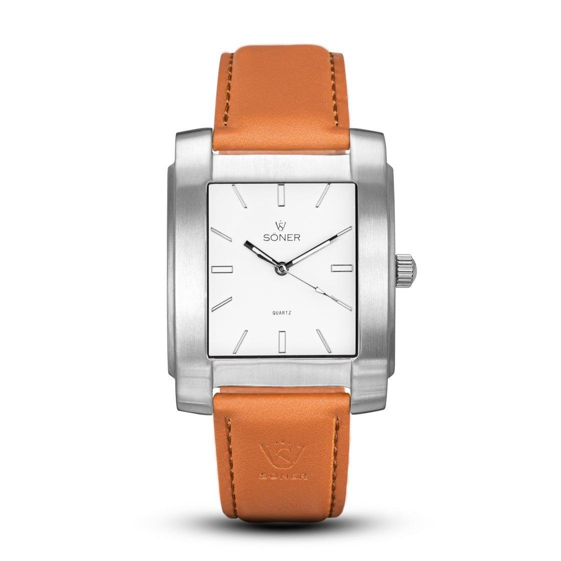 The Legacy Chaillot (3-year Battery) from Söner Watches boasts a silver metallic frame and a white face adorned with minimalist markings and hands. Enhanced by a tan leather strap featuring visible stitching, the watch elegantly displays the brand name Soner on its face.