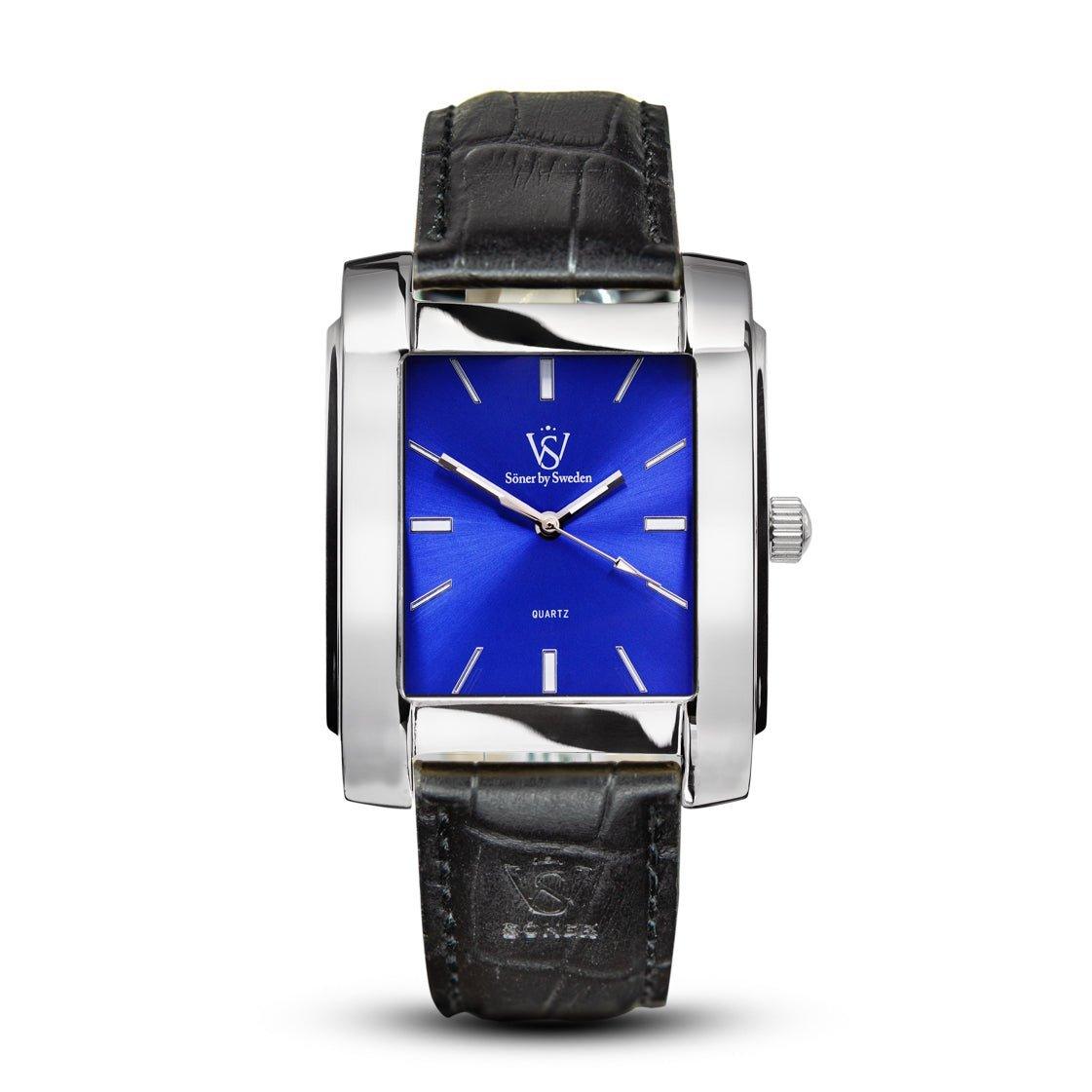 The men's Legacy Glocke watch boasts a rectangular silver case and a sophisticated blue dial adorned with silver hour markers, complemented by a black leather strap. The elegant face features the inscriptions "Stone by Sweden" and "Quartz." Elevate your style with the timeless design of this exceptional rectangular watch, backed by a 3-year battery.