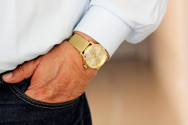 man-wearing-blue-jeans-and-a-gold-watch